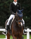 A rider in equestrian competition attire sits on a dark brown horse in an outdoor arena. The rider wears a navy helmet, a black sweater with white trim, white breeches, and black boots.